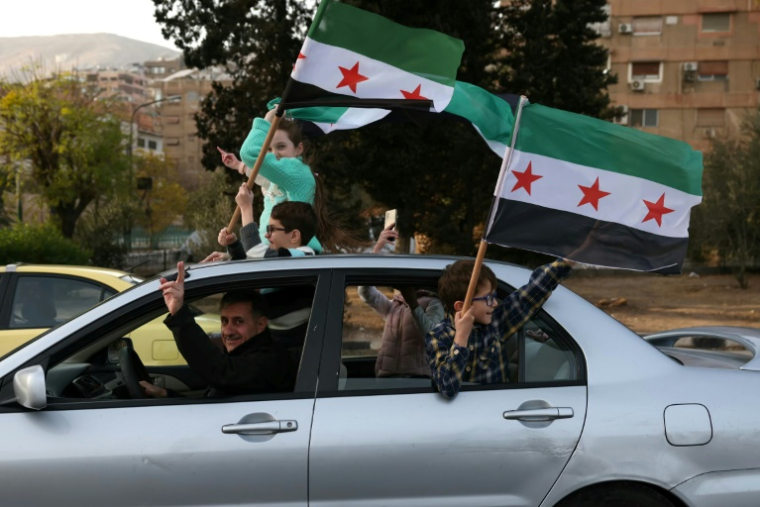 Des Syriens célèbrent la chute du pouvoir en arborant le drapeau de la révolte à Damas, le 10 décembre 2024 ( AFP / OMAR HAJ KADOUR )