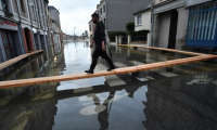 Un homme marche sur des planches surélevées pour circuler dans une rue inondée de Redon, le 30 janvier 2025, en Ille-et-Vilaine ( AFP / JEAN-FRANCOIS MONIER )