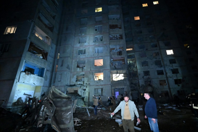 Des habitants devant un immeuble résidentiel touché par une frappe russe nocturne, le 21 septembre 2024 à Kharkiv, en Ukraine ( AFP / SERGEY BOBOK )