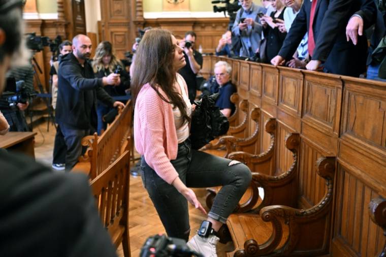 L'Italienne Ilaria Salis, accusée d'avoir attaqué des néo-nazis présumés, montre à des proches son bracelet de surveillance fixé à sa cheville, à l'ouverture de son procès, le 24 mai 2024 à Budapest, en Hongrie ( AFP / Attila KISBENEDEK )