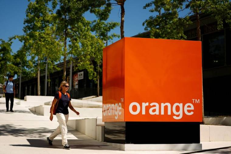Une femme passe devant le logo d'Orange au siège de la société à Issy-les-Moulineaux