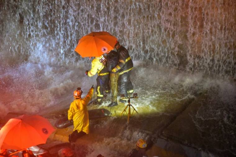 Des sauveteurs recherchent des personnes coincées sous un mur qui s'est effondré sur plusieurs véhicules après de fortes pluies sur l'avenue 27 Février de Saint Domingue, le 18 novembre 2023 ( AFP / Felix Leon )
