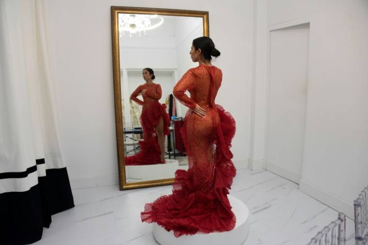 Virginia Cuaresma essaie une robe de flamenco rouge dans l'atelier du couturier espagnol Luis Fernandez, le 8 avril 2024 à Séville ( AFP / CRISTINA QUICLER )
