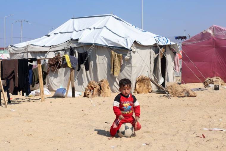 Un garçon palestinien déplacé, qui a fui sa maison à cause des frappes israéliennes, est assis sur un ballon à Rafah