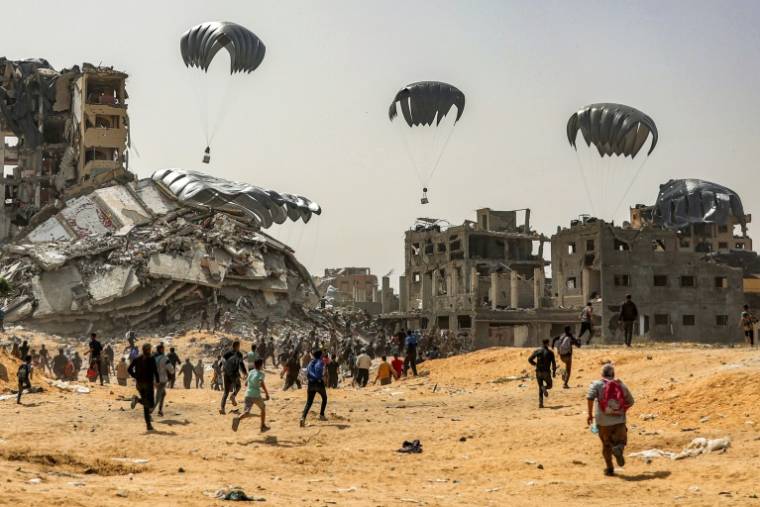 Des Palestiniens se ruent vers des parachutes d'aide humanitaire qui arrivent sur le nord de la bande de Gaza, le 23 avril 2024 ( AFP / - )