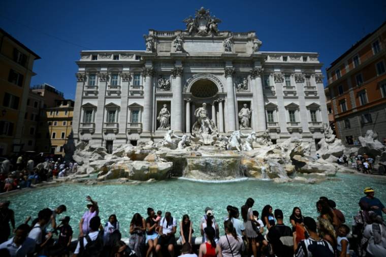 Des touristes se rafraîchissent à la fontaine de Trévi, à Rome, lors d'une vague de chaleur, le 21 août 2023 ( AFP / FILIPPO MONTEFORTE )