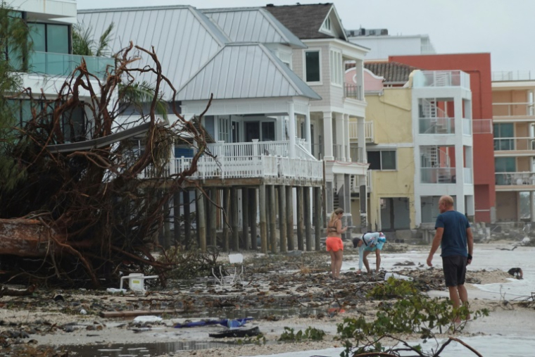 Des arbres et des débris gisent sur la plage alors que des gens marchent après que l'ouragan Hélène a frappé la région, le 28 septembre 2024, à Treasure Island, en Floride ( GETTY IMAGES NORTH AMERICA / JOE RAEDLE )