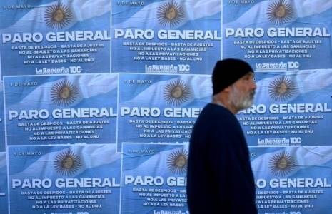 Un homme passe devant des affiches annonçant la grève général à Buenos Aires, le 9 mai 2024 ( AFP / Luis ROBAYO )