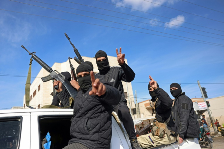 Des combattants de la branche militaire du Hamas font le V de la victoire dans une rue de Deir el-Balah, dans le centre de la bande de Gaza, le 19 janvier 2025 ( AFP / BASHAR TALEB )