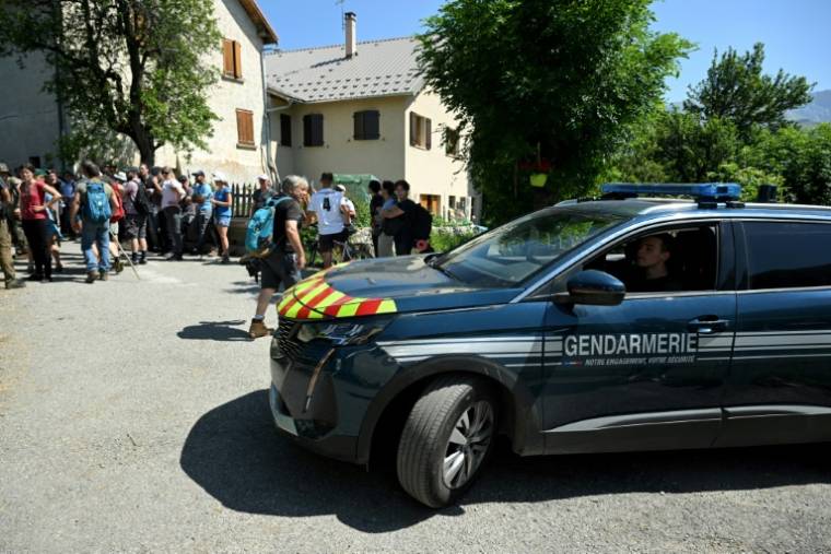 Un véhicule de la gendarmerie près de bénévoles participant aux recherches d'Emile, disparu deux jours avant, le 10 juillet 2023 au Vernet, dans les Alpes-de-Haute-Provence ( AFP / NICOLAS TUCAT )