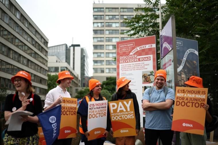 Des pancartes de la British Medical Association (BMA) réclamant de meilleurs salaires sur un piquet de grève devant l'hôpital St Thomas, pendant une grève des jeunes médecins, le 27 juin 2024 à Londres ( AFP / HENRY NICHOLLS )