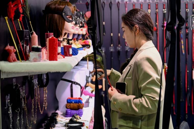 Une visiteuse regarde des jouets sexuels exposés au salon international des produits pour adultes à Shanghai, le 19 avril 2024 en Chine ( AFP / STR )