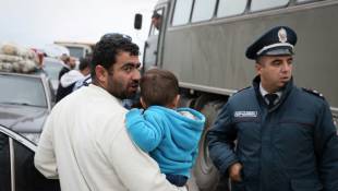 Un réfugié portant un enfant s'entretient avec un policier près de la ville frontalière de Kornidzor, en Arménie, le 25 septembre 2023 ( AFP / ALAIN JOCARD )