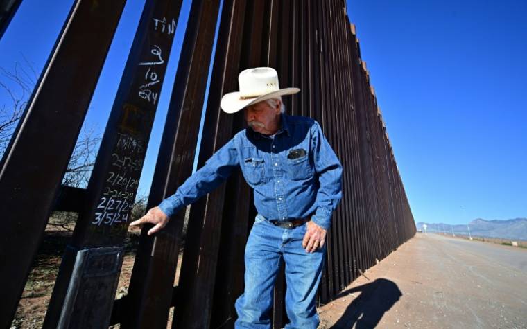 L'élveur John Ladd montre des dates indiquant les dernières réparations effectuées sur le mur frontalier entre les Etats-Unis et le Mexique, régulièrement endommagé par des migrants, le 17 avril 2024 près de Palominas, en Arizona  ( AFP / Frederic J. BROWN )