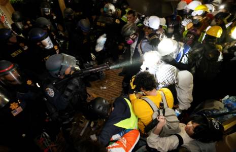 Des policiers font face aux étudiants pro-palestiniens après avoir détruit une partie de la barricade érigée sur le campus de l'Université de Californie à Los Angeles (UCLA), le 2 mai 2024 ( AFP / Etienne LAURENT )