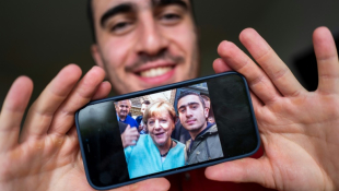 Le réfugié syrien Anas Modamani montre le selfie qu'il a fait avec la chancelière allemande Angela Merkel en septembre 2015, dans son appartement à Berlin, le 1er septembre 2021 ( AFP / John MACDOUGALL )