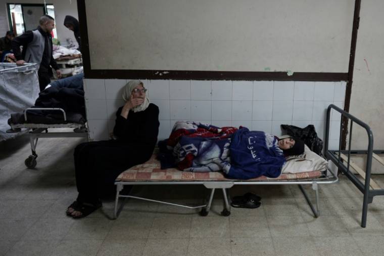 Une femme palestinienne assise à côté d'un patient dans un hôpital du centre de la bande de Gaza le 3 avril 2024 ( AFP / - )
