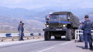 Un camion de Casques bleus russes traverse la frontière du côté azerbaïdjanais devant les forces de police arméniennes (d) près de Kornidzor, le 22 septembre 2023 en Arménie ( AFP / ALAIN JOCARD )