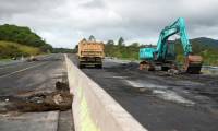 Des engins de chantier enlèvent des débris sur la route RT1 qui mène à l'aéroport international de Nouméa, le 19 mai 2024 ( AFP / Delphine Mayeur )
