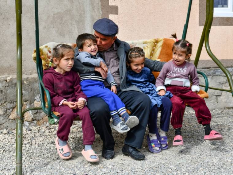 Djamoliddine Makhmaliev, déplacé climatique, avec ses petits-enfants, dans sa nouvelle maison du district de Khourosson, le 26 mars 2024 au Tadjikistan ( AFP / - )