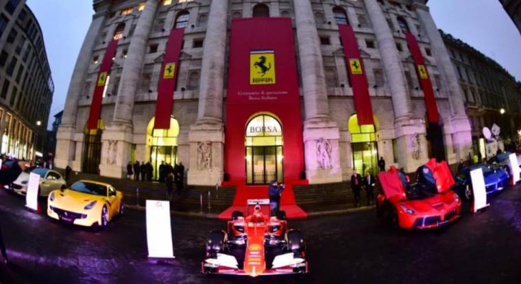 Une monoplace Ferrari exposée parmi d'autres voitures devant la Bourse de Milan le 4 janvier 2016 à Milan.