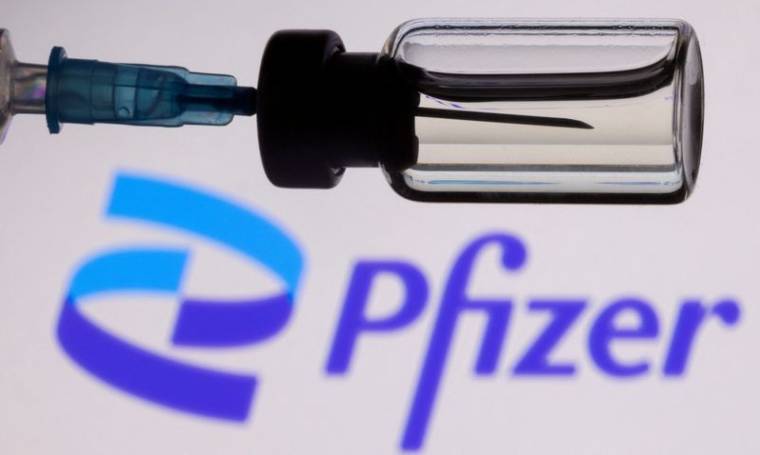 Photo d'illustration d'une seringue devant le logo de Pfizer