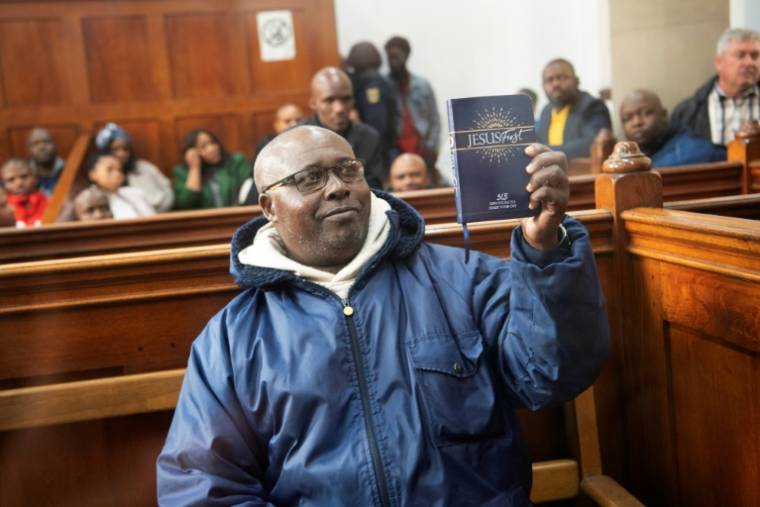 Fulgence Kayishema devant le tribunal du Cap, brandissant son livre de prières,le 26 mai 2023 ( AFP / RODGER BOSCH )