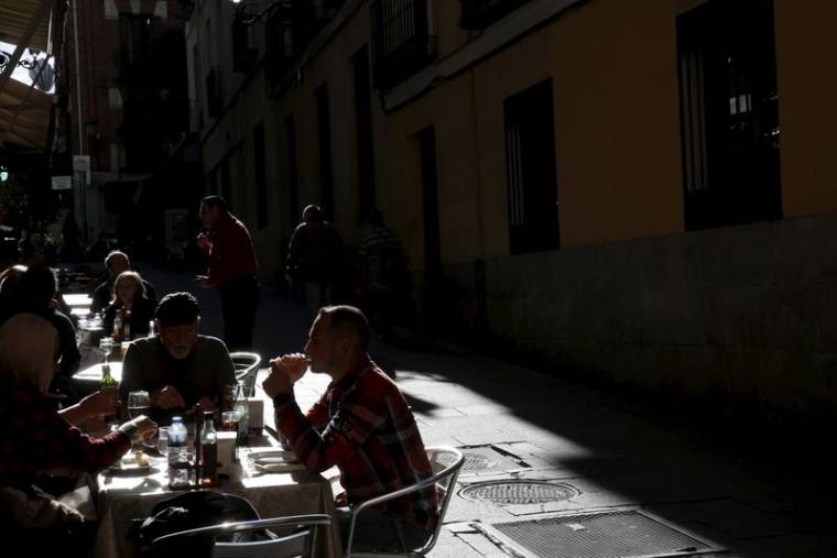 Des personnes déjeunent à des tables en plein air dans un restaurant du centre de Madrid