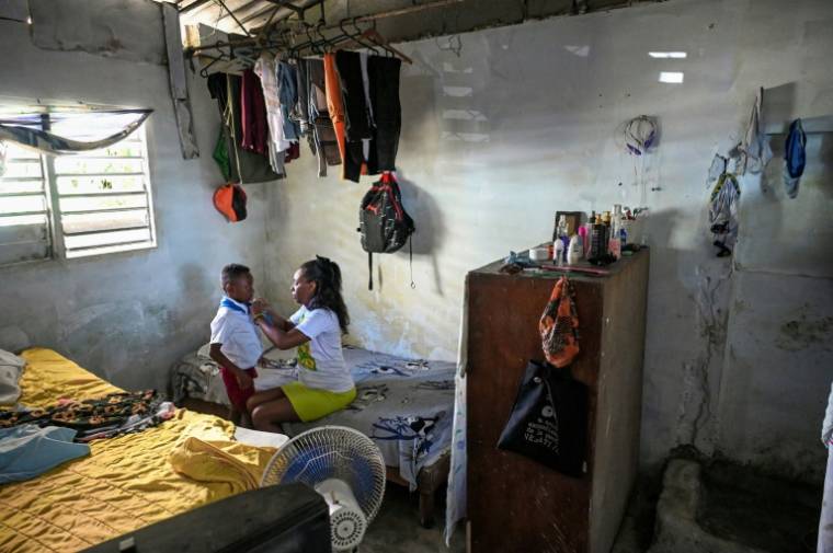 Diana Ruiz enlève l'uniforme scolaire de son fils, chez eux à La Havane, le 27 mars 2024 à Cuba ( AFP / YAMIL LAGE )