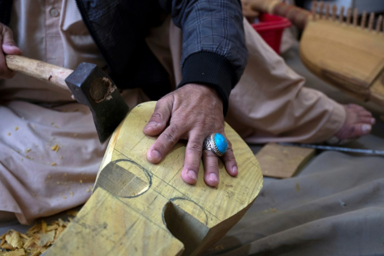 Sakhi, un artisan afghan, utilise une hachette pour fabriquer un rubab, dans un atelier à Herat, le 22 décembre 2024 ( AFP / Wakil KOHSAR )