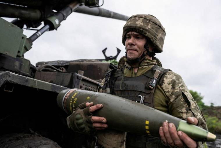 Un militaire ukrainien porte un obus pour un obusier automoteur Caesar avant de tirer en direction des troupes russes près d'Avdiivka