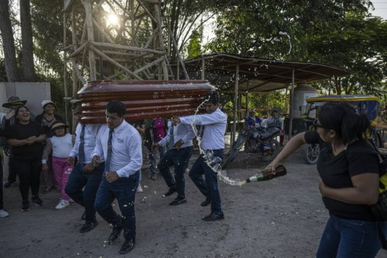 La famille et les proches lancent de la bière sur le cercueil de Marcelino Jamanca lors de ses funérailles, le 2 mai 2024 à Huacho, au Pérou ( AFP / Ernesto BENAVIDES )