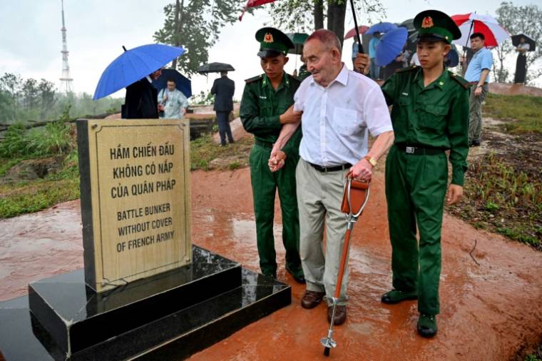 Le vétéran français Jean-Yves Guinard, aidé par des soldats vietnamiens, devant une plaque commémorative au sommet de la colline Him Lam (colline Béatrice), le 6 mai 2024 à Dien Bien Phu ( AFP / Nhac NGUYEN )