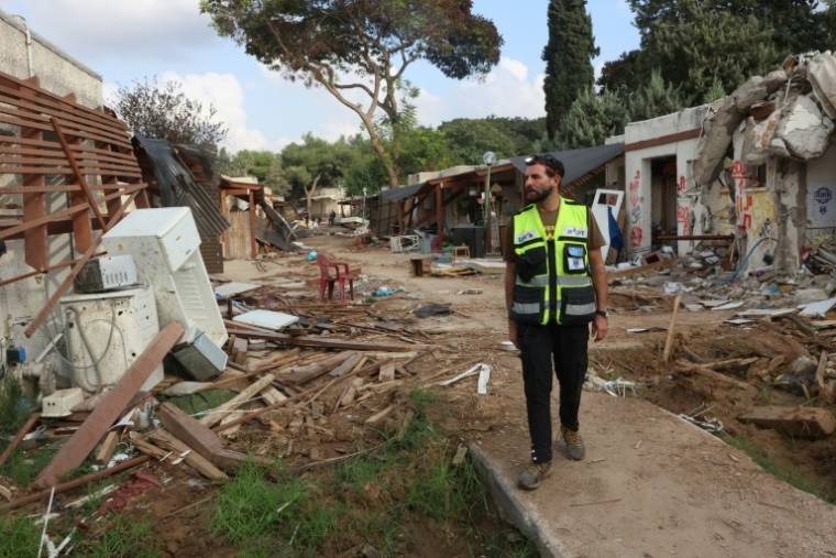 Un membre de l'équipe d'intervention d'urgence juive ultra-orthodoxe israélienne Zaka passe devant les décombres de maisons dans le kibboutz Kfar Aza, près de la frontière avec la bande de Gaza, le 14 novembre 2023 ( AFP / GIL COHEN-MAGEN )