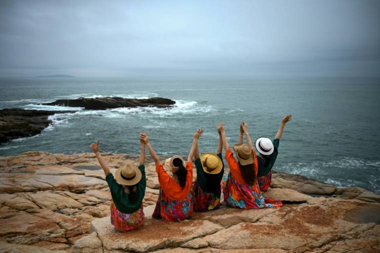 Des personnes posent pour des photos devant le détroit de Taïwan sur un site touristique appelé "68 milles marins" situé sur l'île de Pingtan, dans la province chinoise du Fujian, dans le sud-est du pays, à l'endroit de Chine continentale le plus proche de l'île principale de Taïwan, le 24 mai 2024. ( AFP / Greg Baker )