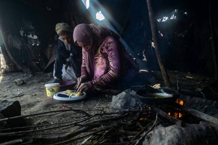 Une femme cuisine sur un feu de brindilles, dans le camp de réfugiés de Al-Younani, dans les environs de Raqa, en Syrie, le 8 février 2024 ( AFP / Delil SOULEIMAN )