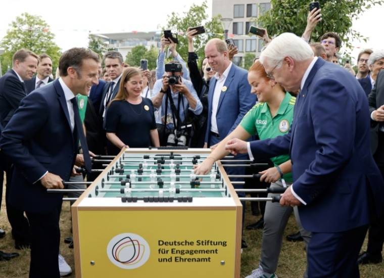 Le président français Emmanuel Macron (G) et son holomogue allemand Frank-Walter Steinmeier (D) jouent au baby-foot lors de la "Fête de la démocratie" qui célèbre le 75e anniversaire de la Constitution allemande d'après-guerre, le 26 mai 2024 à Berlin ( AFP / Ludovic MARIN )