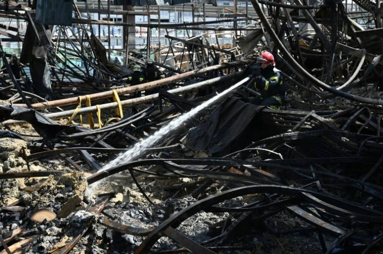 Les pompiers dans les décombres d'un supermarché détruit par une frappe russe, à Kharkiv, en Ukraine, le 26 mai 2024 ( AFP / SERGEY BOBOK )