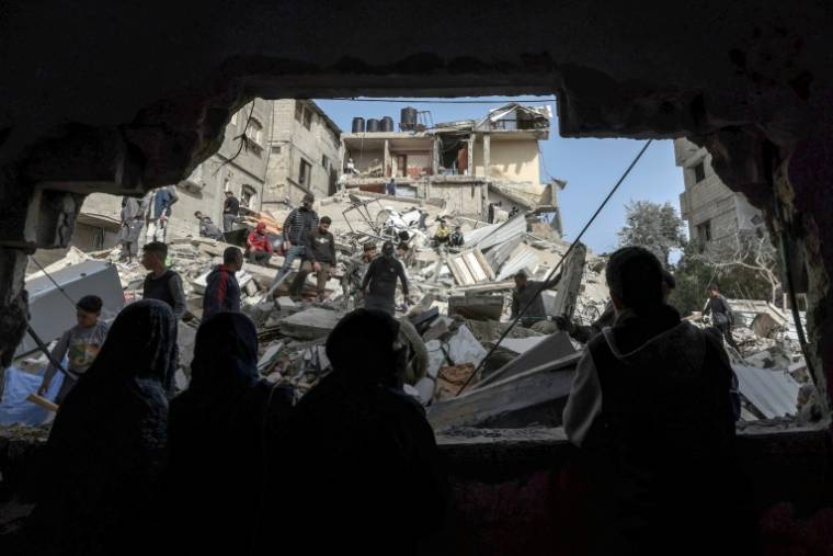 Des Palestiniens dans les décombres de bâtiments détruits par un bombardement israélien nocturne à Rafah, dans le sud de la bande de Gaza, le 27 mars 2024 ( AFP / MOHAMMED ABED )