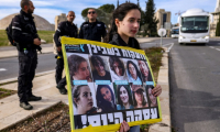 Une manifestante tient une pancarte avec des photos d'otages à Gaza lors d'un rassemblement appelant à une trêve dans la guerre contre le Hamas et à la libération des otages, devant le bureau du Premier ministre israélien à Jérusalem, le 14 janvier 2024 ( AFP / HAZEM BADER )