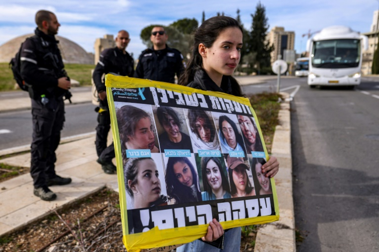 Une manifestante tient une pancarte avec des photos d'otages à Gaza lors d'un rassemblement appelant à une trêve dans la guerre contre le Hamas et à la libération des otages, devant le bureau du Premier ministre israélien à Jérusalem, le 14 janvier 2024 ( AFP / HAZEM BADER )