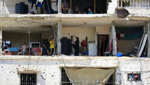 Des familles palestiniennes retournent dans leurs maisons gravement endommagées dans un immeuble touché lors d'un précédent bombardement israélien, dans la ville de Khan Younés, dans le sud de la bande de Gaza, le 30 juin 2024 ( AFP / Eyad BABA )