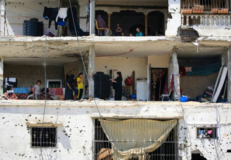 Des familles palestiniennes retournent dans leurs maisons gravement endommagées dans un immeuble touché lors d'un précédent bombardement israélien, dans la ville de Khan Younés, dans le sud de la bande de Gaza, le 30 juin 2024 ( AFP / Eyad BABA )