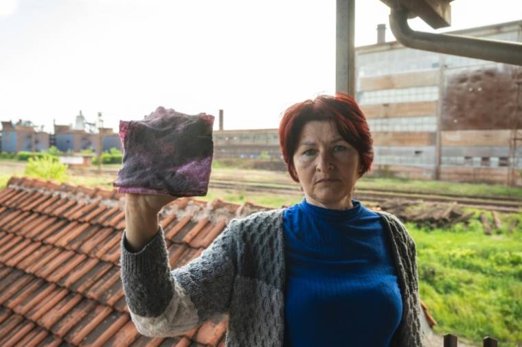 Dragana Milic montre un chiffon noirci après avoir nettoyé une vitre de sa maison située près d'une aciérie exploitée par le groupe chinois HBIS, dans le village de Radinac, le 25 avril 2024 en Serbie ( AFP / Andrej ISAKOVIC )