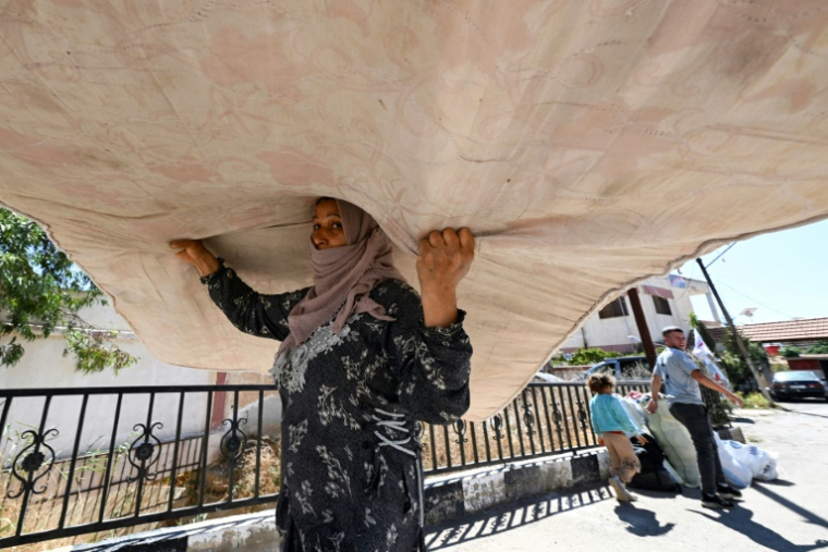 Une femme déplacée portant un matelas arrive en Syrie depuis le Liban, le 2 octobre 2024 ( AFP / LOUAI BESHARA )