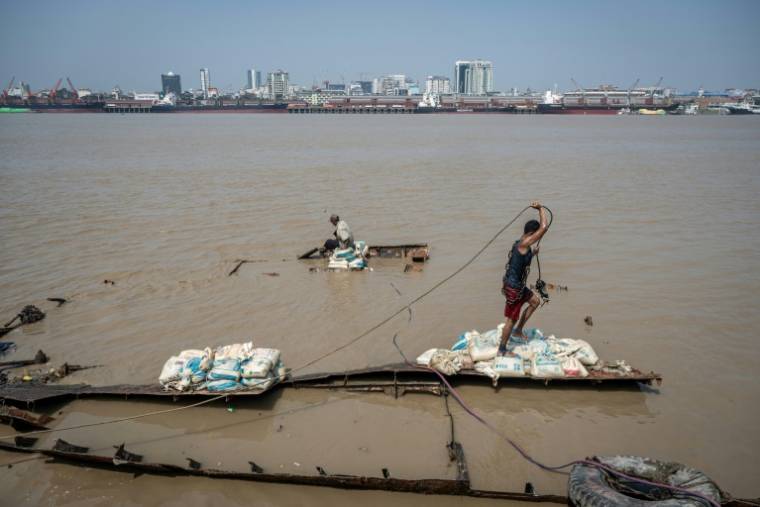 Des hommes récupèrent un navire coulé dans le fleuve Yangon, le 27 février 2024 à Rangoun, en Birmanie ( AFP / Sai Aung MAIN )