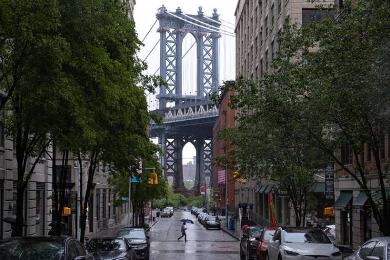 Un piéton passe sur Washington Street dans le quartier de Dumbo à Brooklyn, avec le pont de Manhattan en arrière-plan, à New York