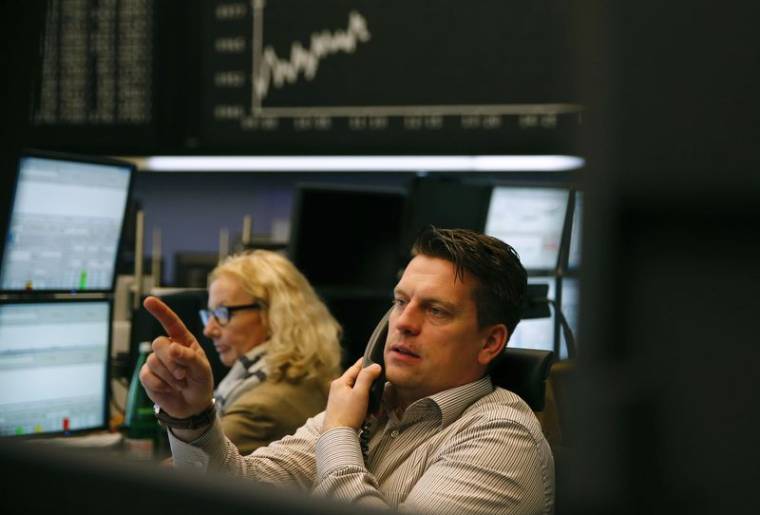 Un trader est assis sous le tableau de l'indice allemand DAX à la bourse de Francfort