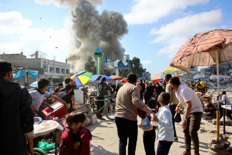 Des Palestiniens observent un nuage de fumée après un bombardement israélien sur la zone du marché de Firas, le 11 avril 2024 à Gaza ( AFP / - )
