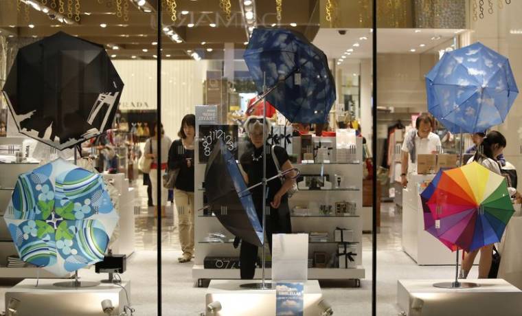 Une femme regarde des parapluies exposés dans un grand magasin de luxe à Tokyo